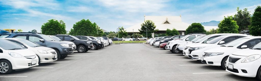 Row of cars parked in an outdoor parking lot under a blue sky
