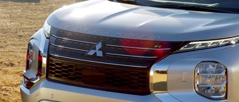 A close up image of a silver mitsubishi outlander's front bumper that has sunlight glinting off of it 