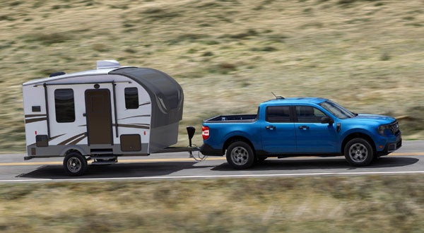 Ford Maverick Driving Down the Road Towing a Camper