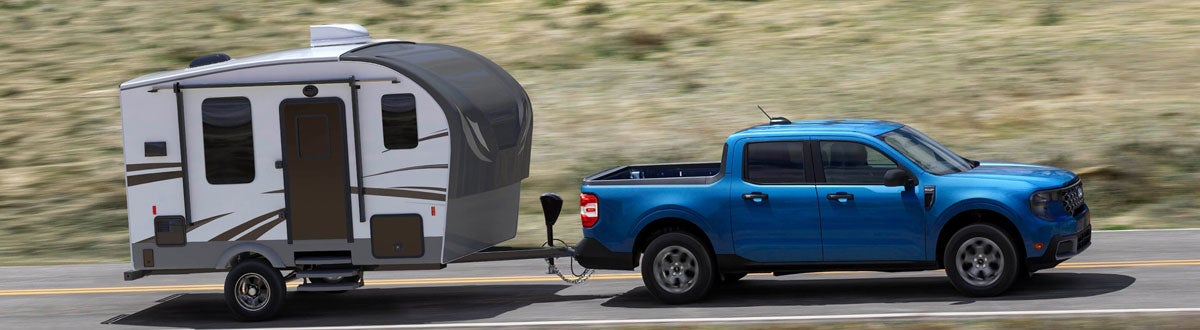 Ford Maverick Driving Down the Road Towing a Camper