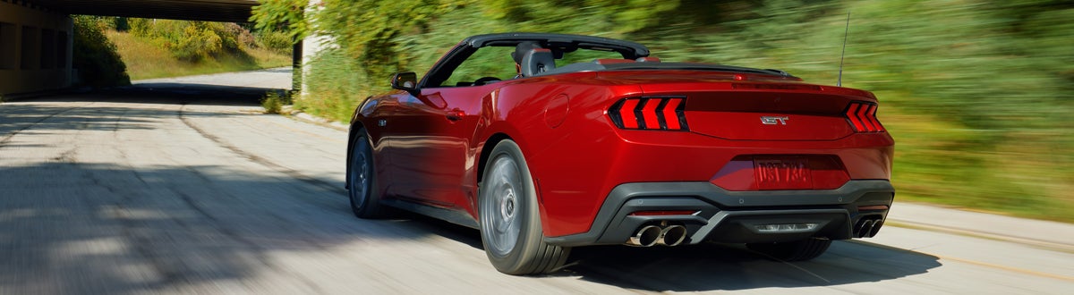 Red Ford Mustang Convertible Driving Down a Road