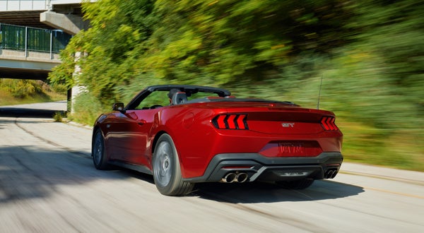 Red Ford Mustang Convertible Driving Down a Road
