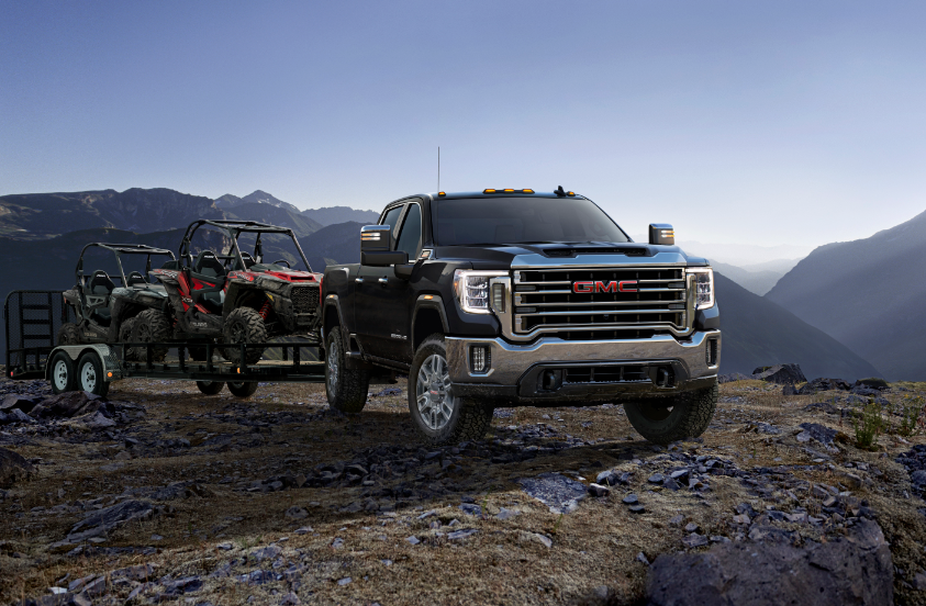 Gray 2023 GMC Sierra 2500 HD parked on rocky hill pulling trailer holding all-terrain cart