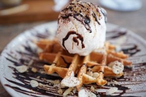 Vanilla ice cream with chocolate syrup sitting on top of a small waffle