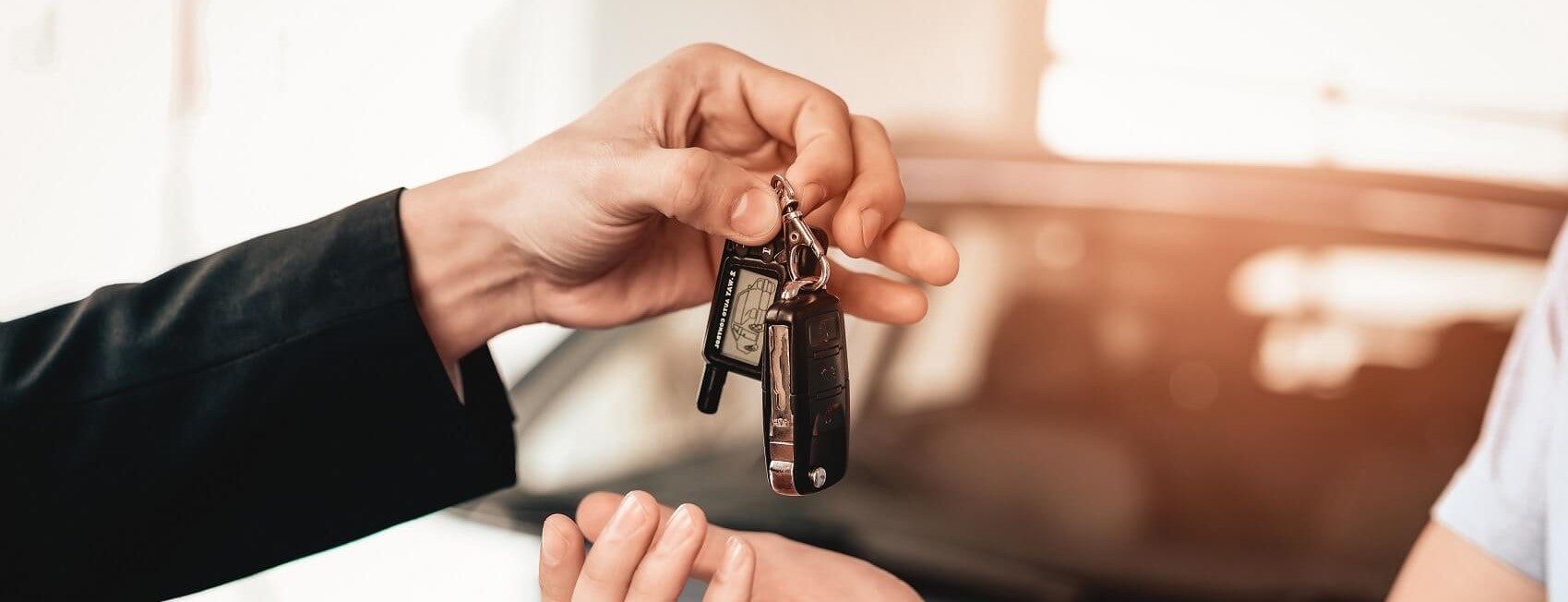 Car Dealer employee handing over car keys to customer