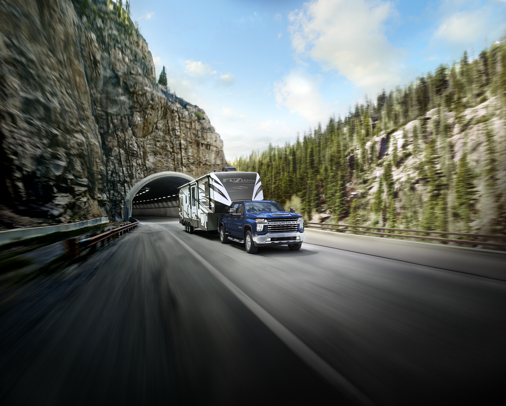 Blue 2021 Chevy Silverado 2500 tows a black and white camper