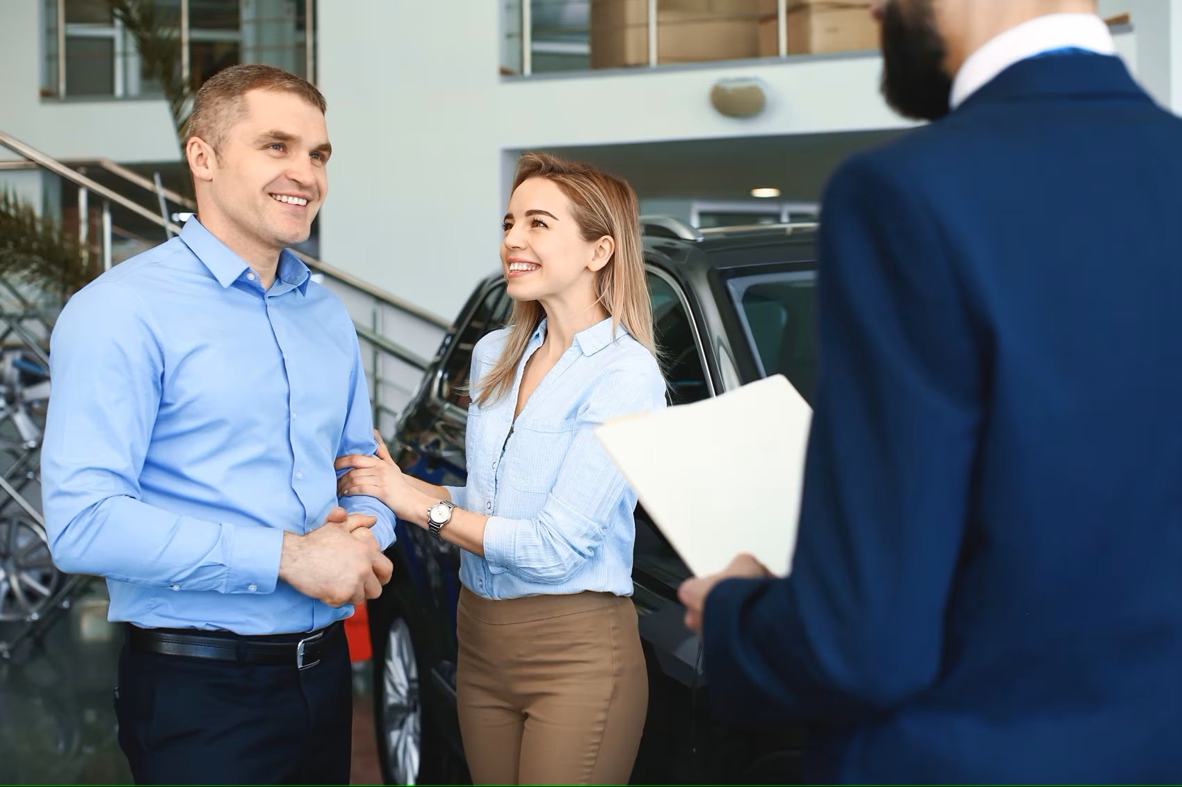 Couple smiling while discussing Chevy financing options with Chevrolet Finance Team member