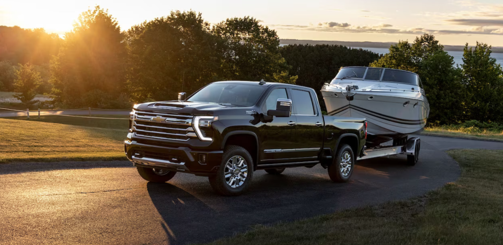 A 2026 Chevy Silverado tows a boat behind it as it drives up a windy road.
