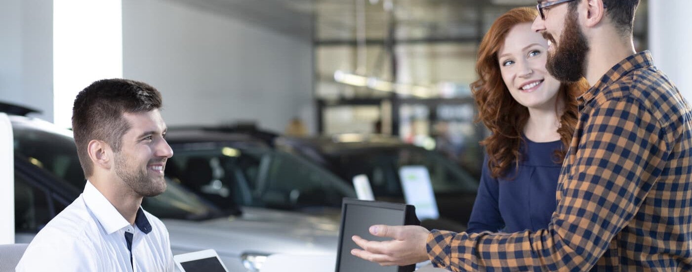 Excited Couple Reviewing Trade in Offer with Salesman