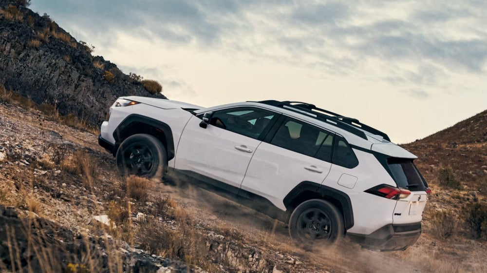 A white Toyota RAV4 is climbing up a rocky, steep incline. 