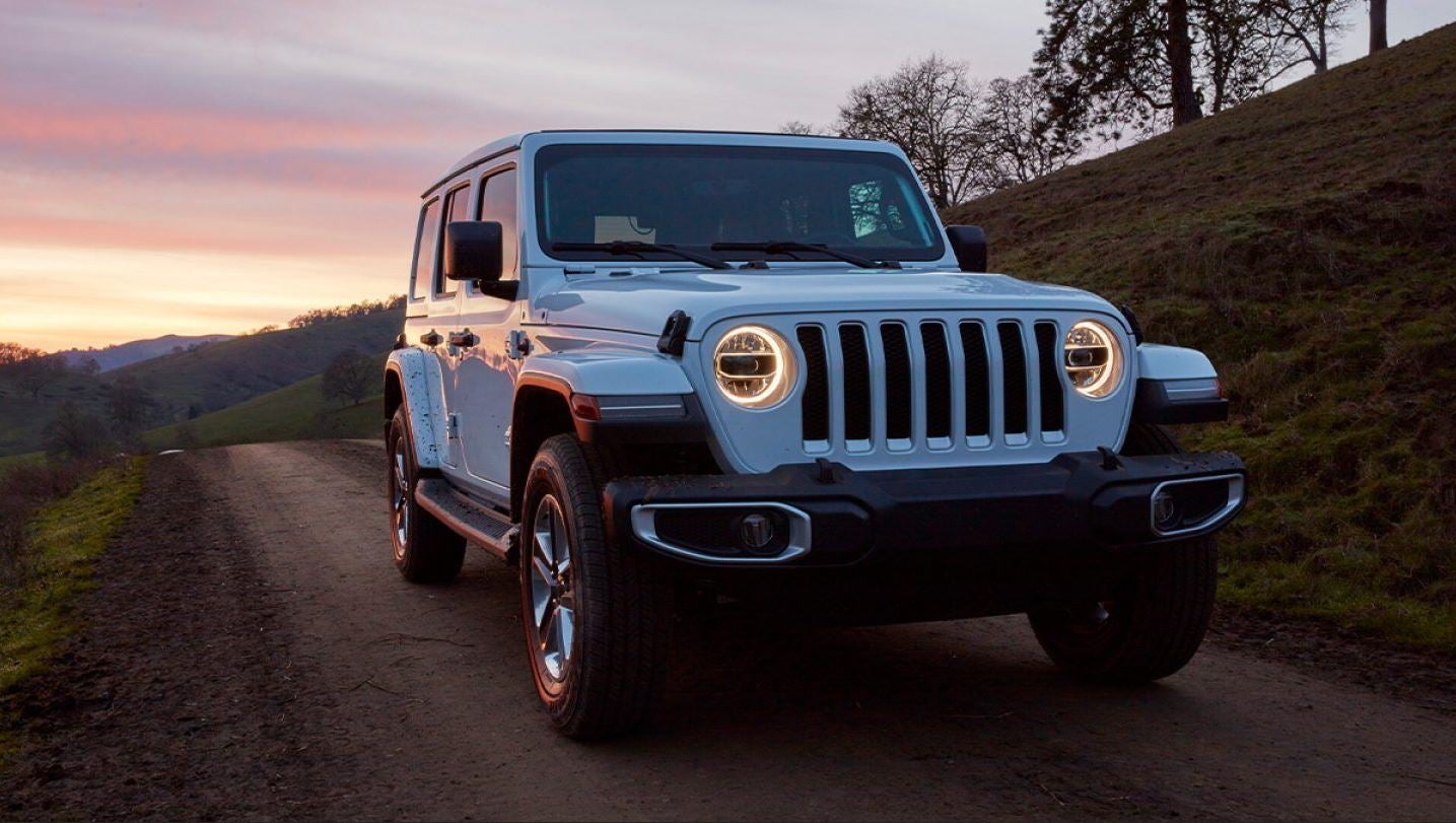 jeep wrangler on dirt road in front of the sunset