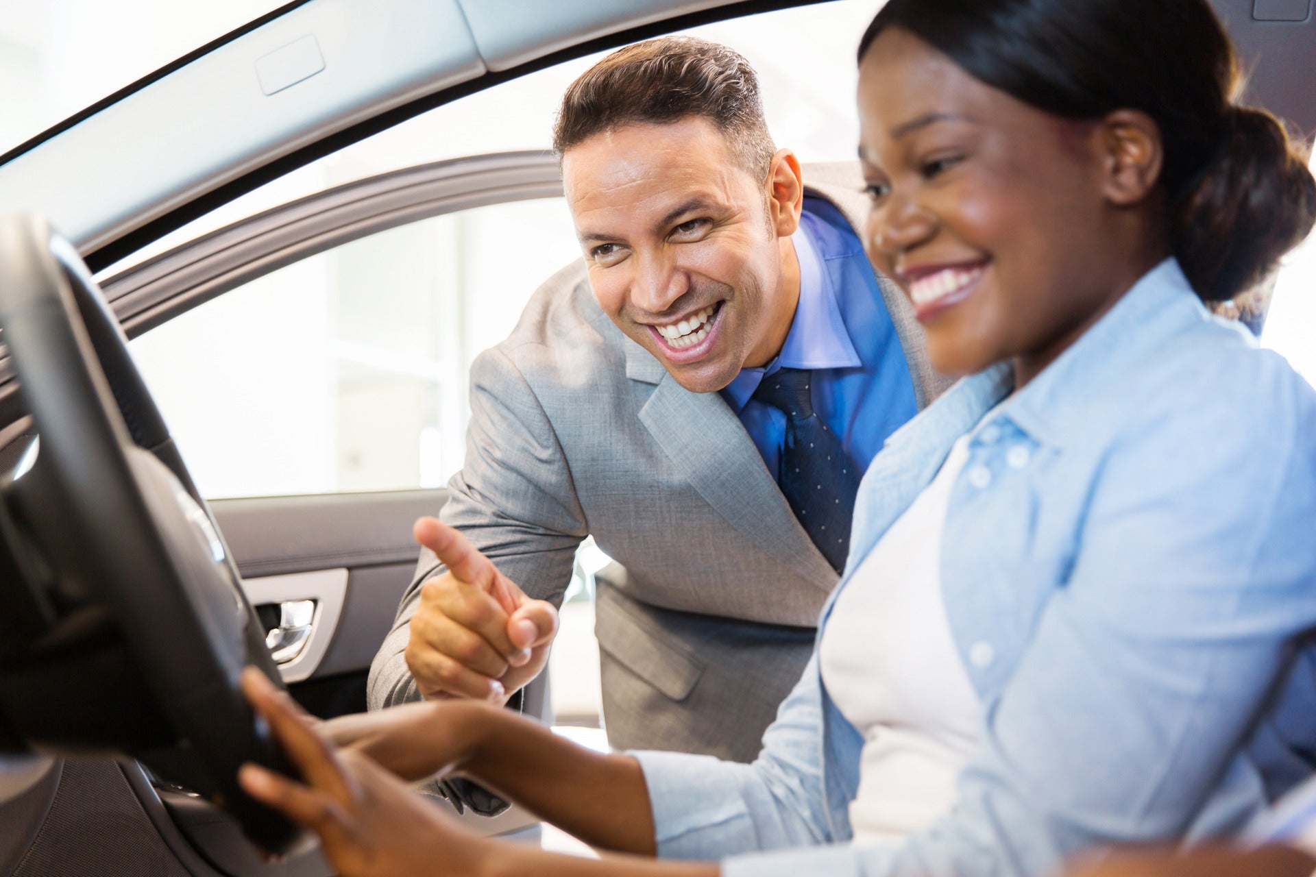 Car salesman showing a vehicle off to a customer who is smiling