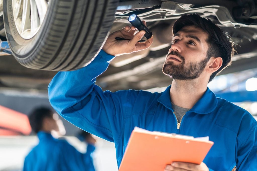 Mechanic inspecting the underside of a vehicle