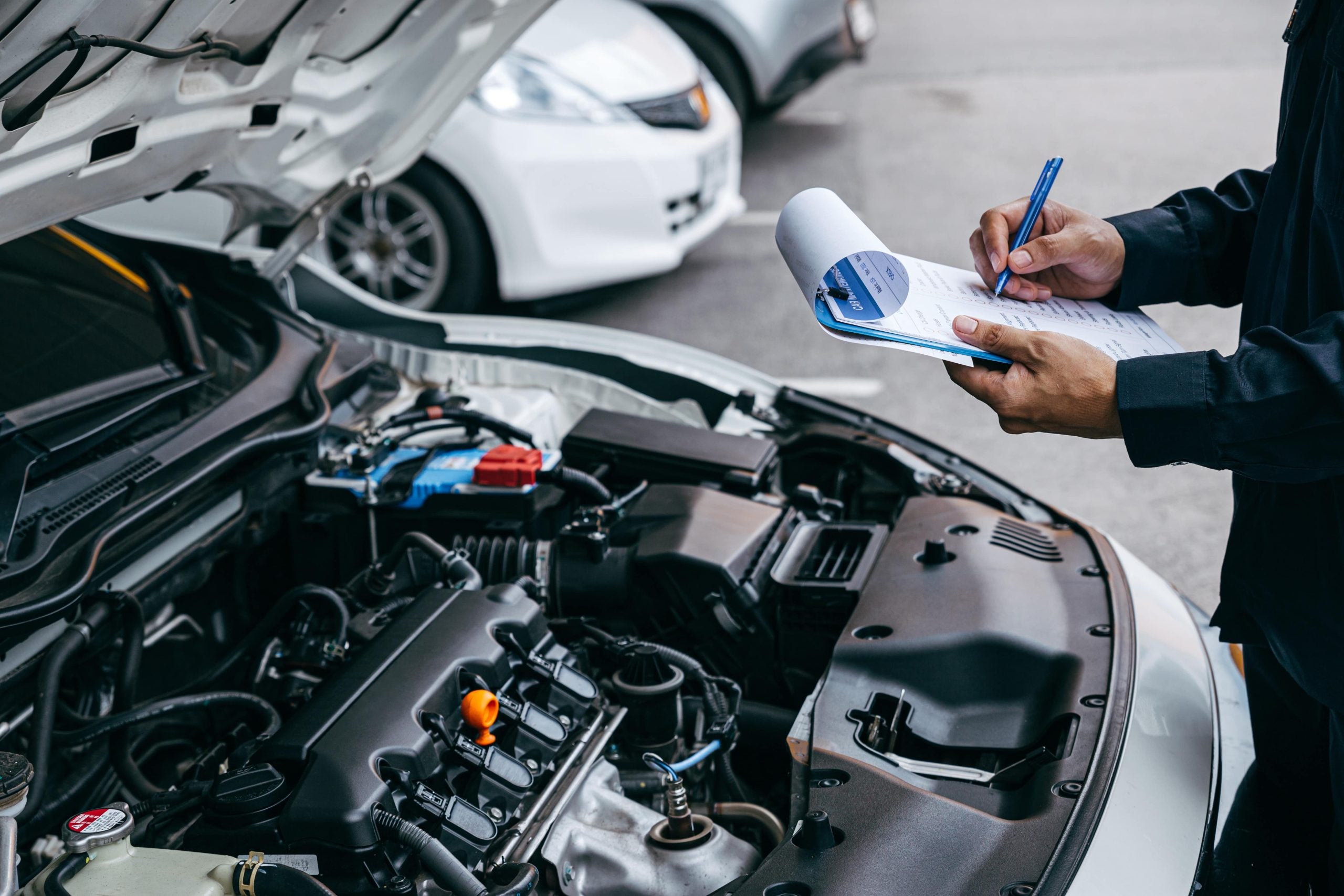 mechanic writing on a notepad while inspecting an engine