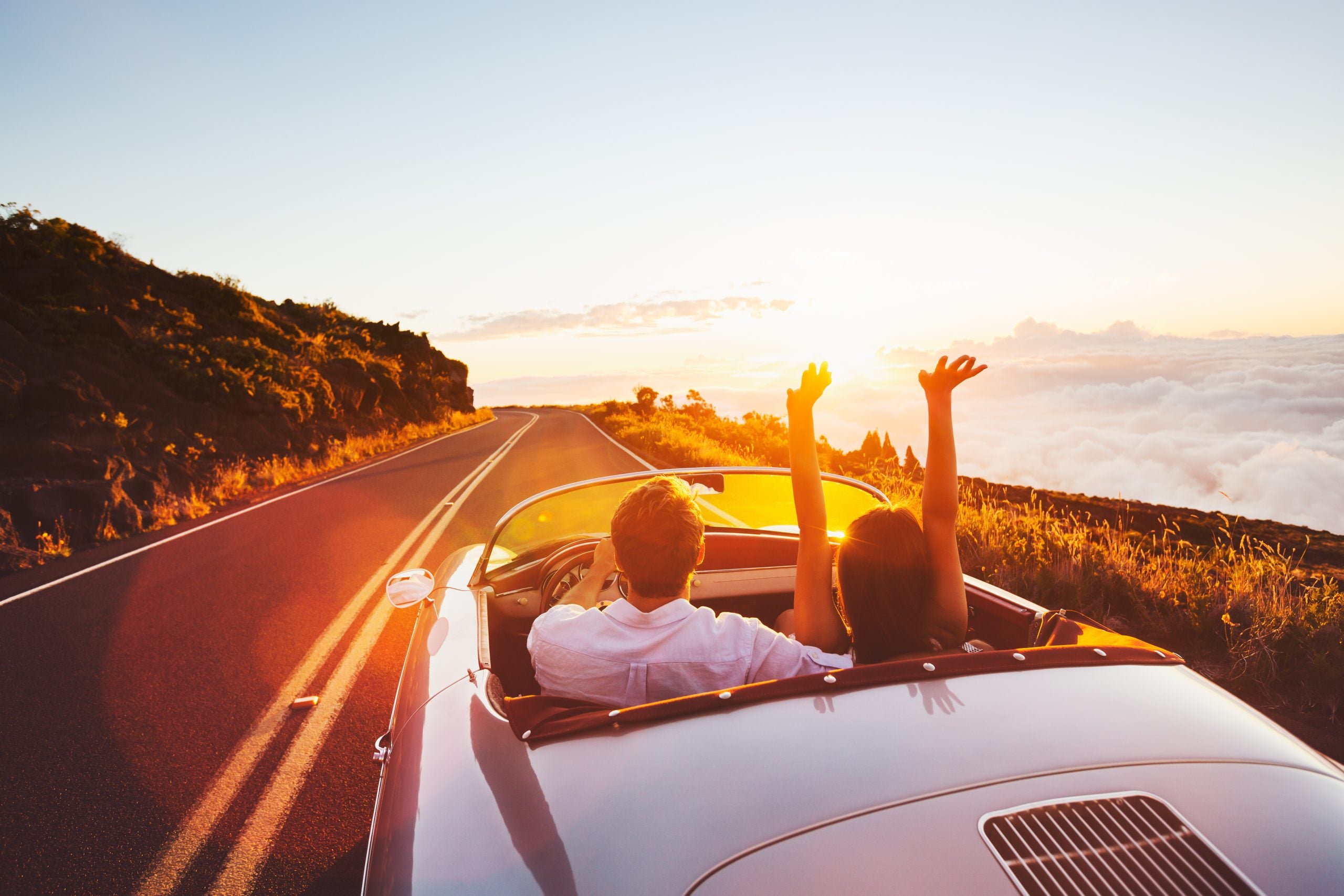 A couple driving down a highway in a convertible