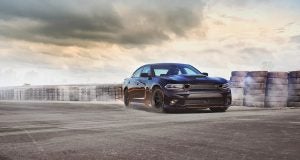 Black 2021 Dodge Charger in front of a parking lot scene with a cloudy sky.