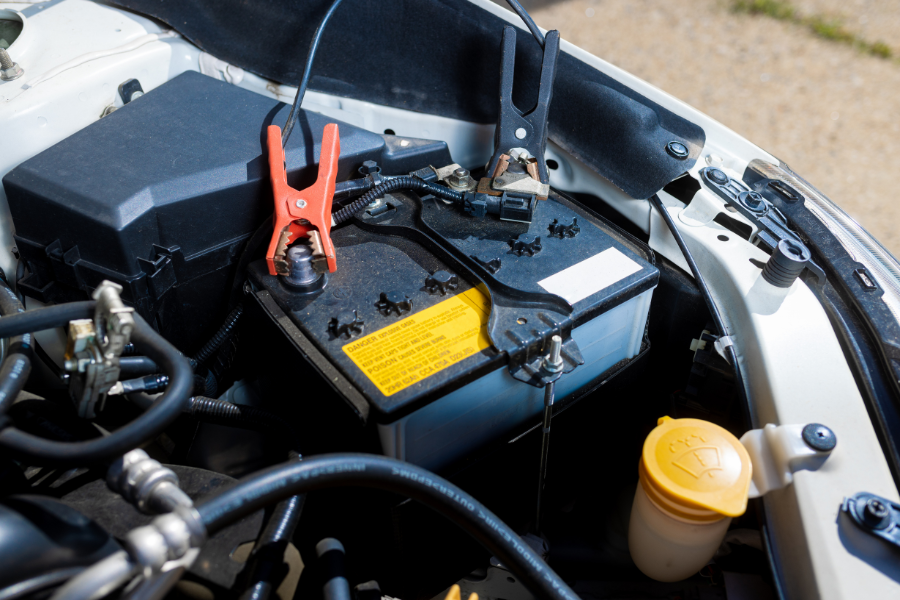 Technician testing a vehicle battery under the hood