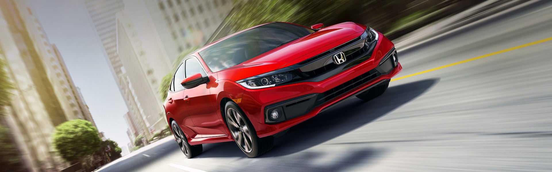 Red Honda Civic sedan driving dynamically on city street, showcasing sleek design and performance - Priority Honda Roanoke