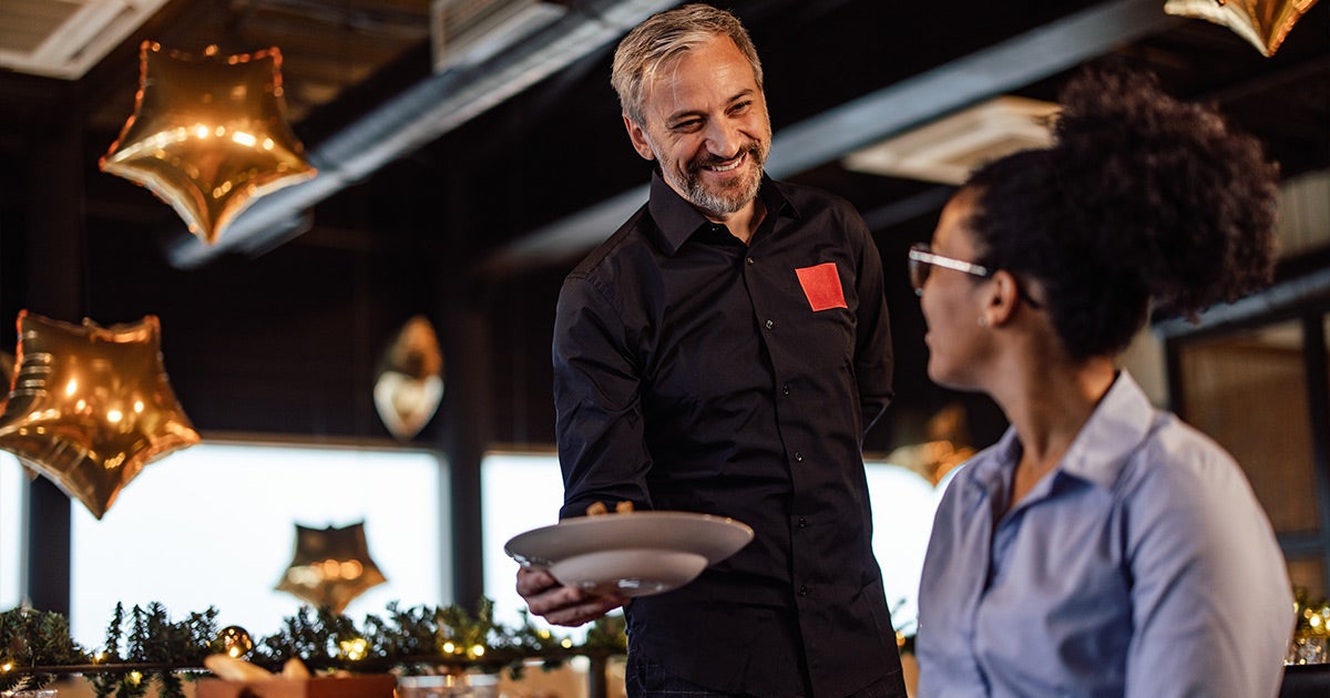 Restaurant or catering setting with staff, golden star-shaped balloons, and festive decor.
