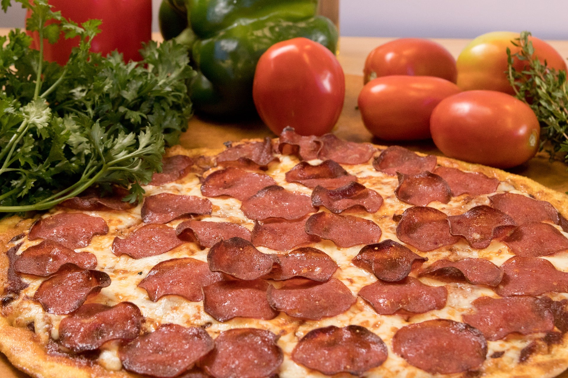 A pepperoni pizza next to some vegetables