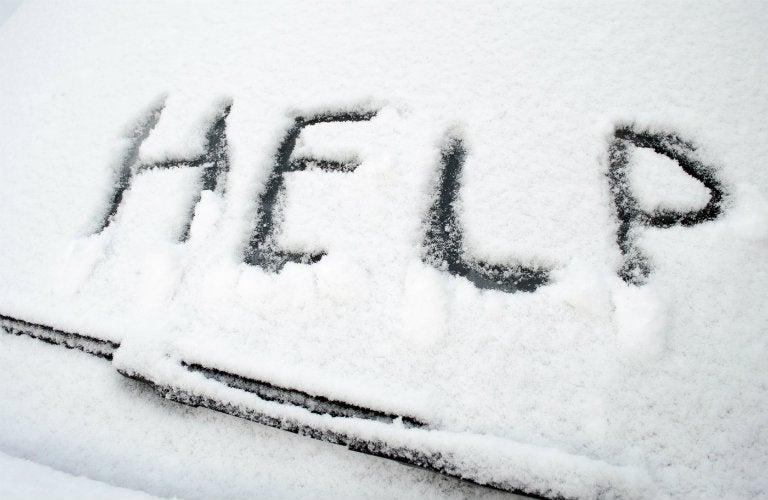 Snow-covered-windshield-wiper-with-help-written-in-snow