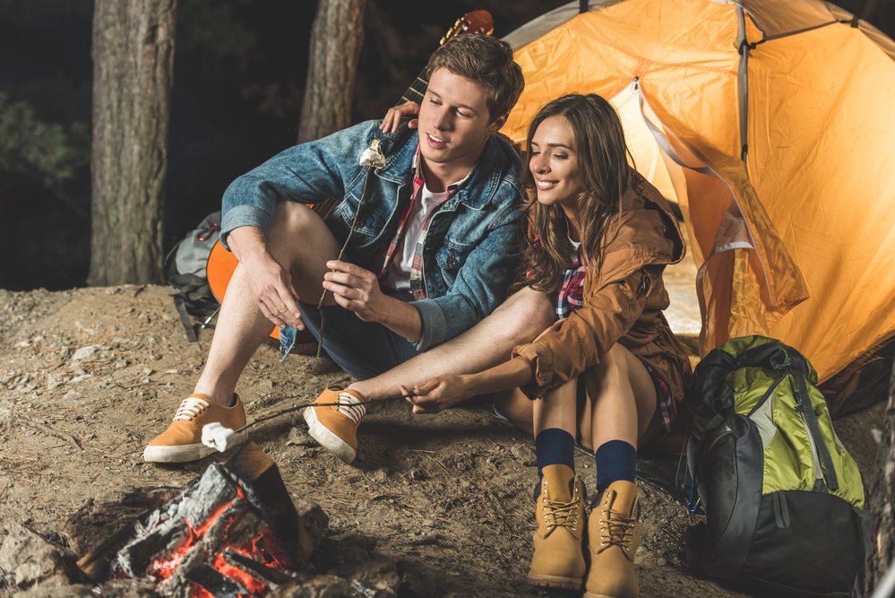 2 people camping, sitting outside their tent