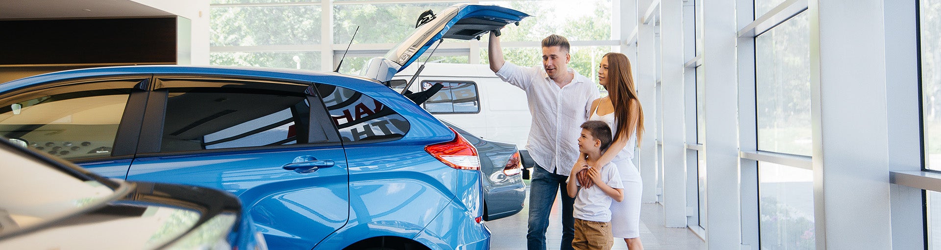 A family looking into the open back of a blue Ford Focus hatchback.