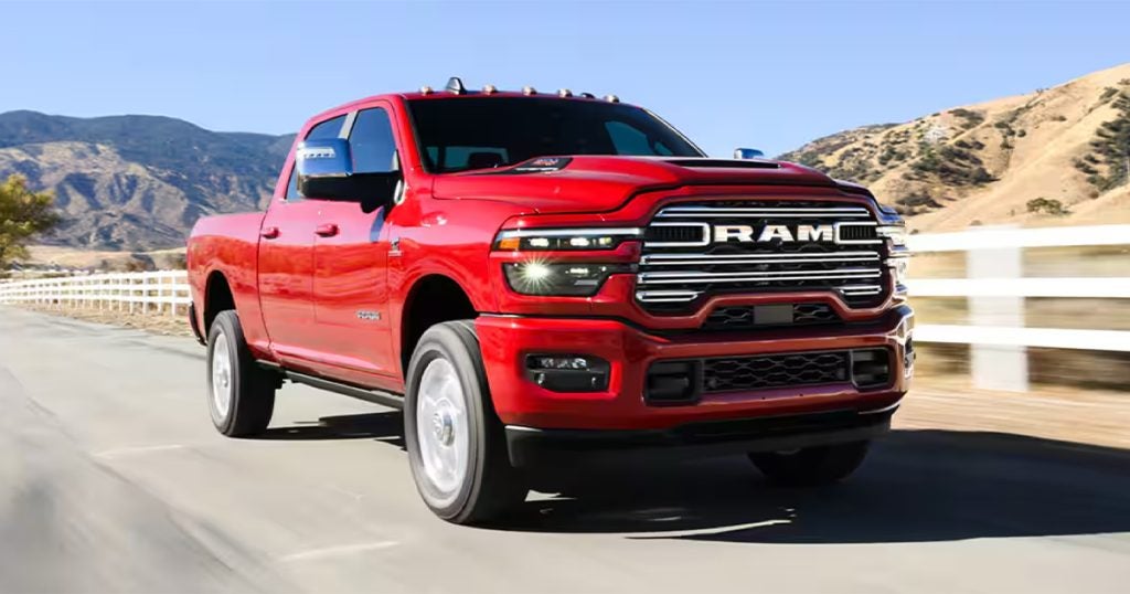 A 2025 Ram 2500 truck driving down a road by a white fence.
