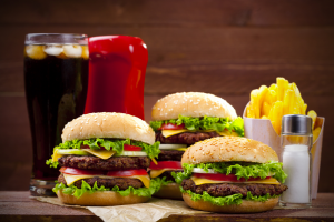Cheeseburgers, fries, drink, and ketchup on a table
