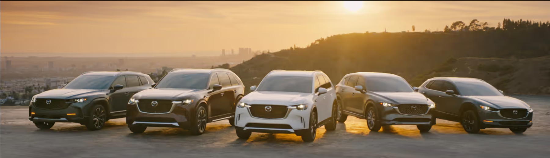 The 2026 Mazda SUV lineup sits parked side by side overlooking a hill.