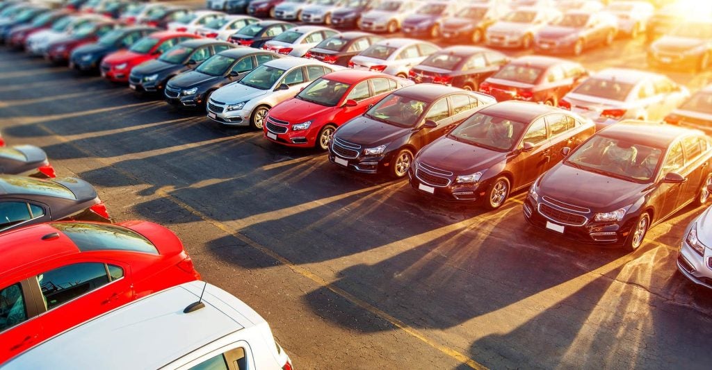 The sun sets on an overview of a used car lot. 