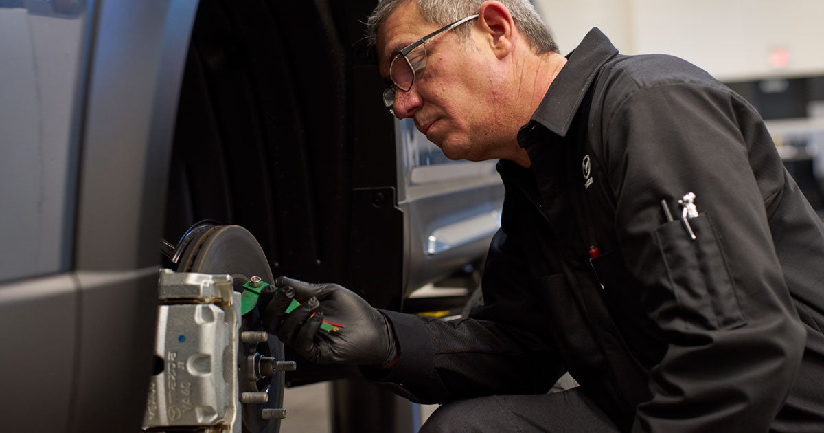 A service technician replacing a vehicle's brake pad.