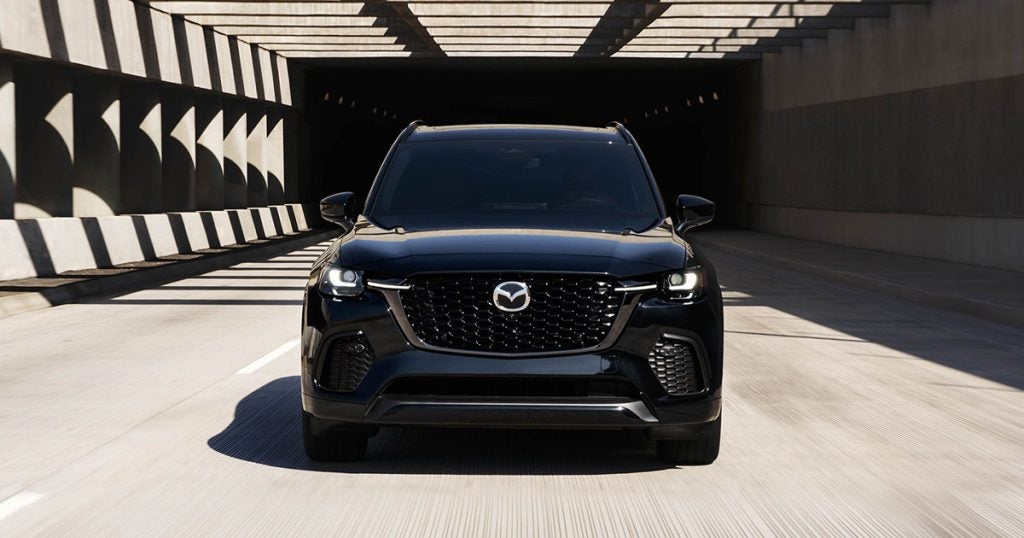 2025 Mazda CX-70 in the jet black mica color driving down the highway.