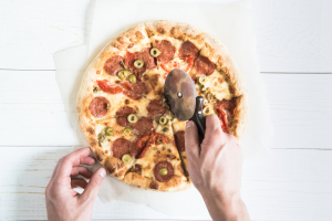 Pepperoni pizza being cut