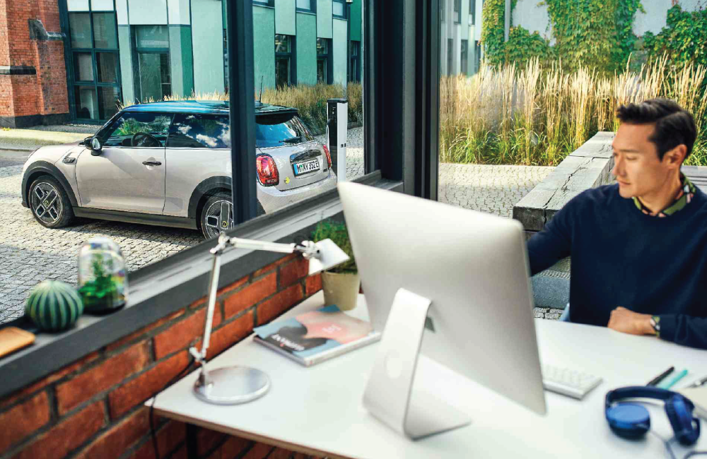 Man in a corner office with a MINI Cooper right outside the window