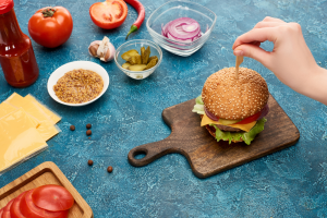 Cheeseburger on the table surrounded by vegetables