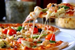 Slice of pizza being taken from a whole pizza