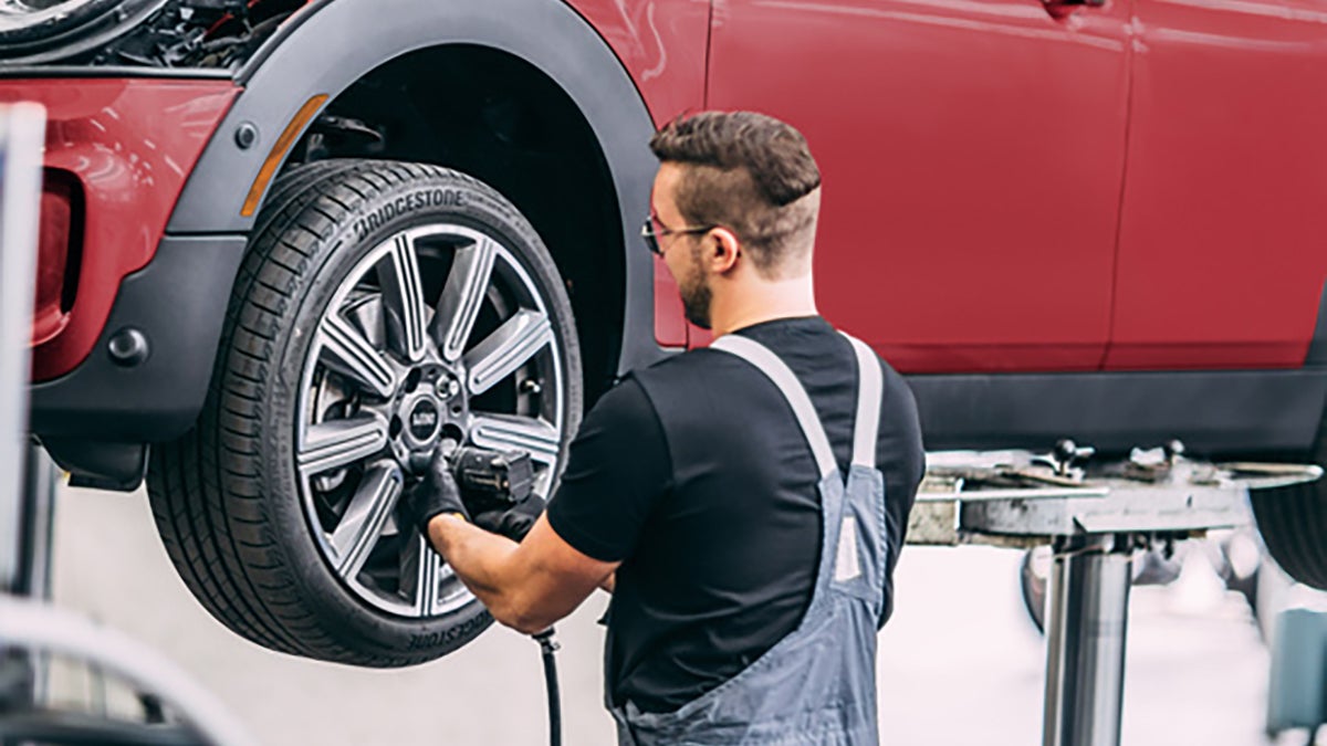 MINI technician working on a MINI Cooper in a clean service bay