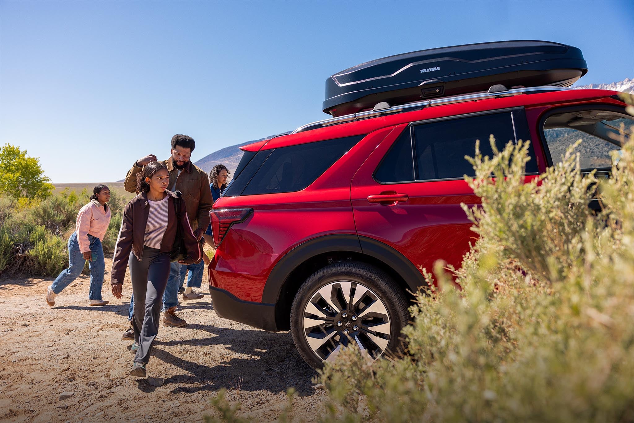 Family walking around the rear of a parked 2026 Ford Explorer in the desert