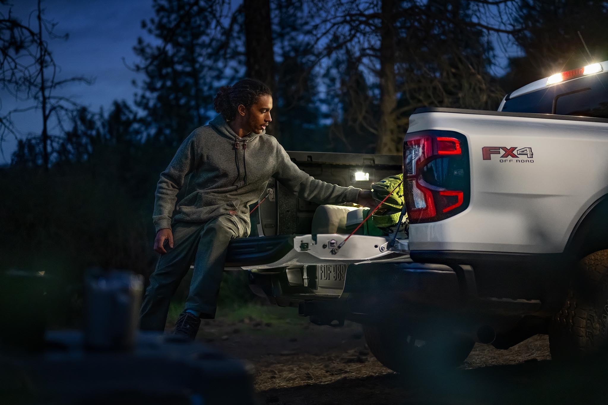 Person loading gear into the open bed of a 2026 Ford Ranger XLT