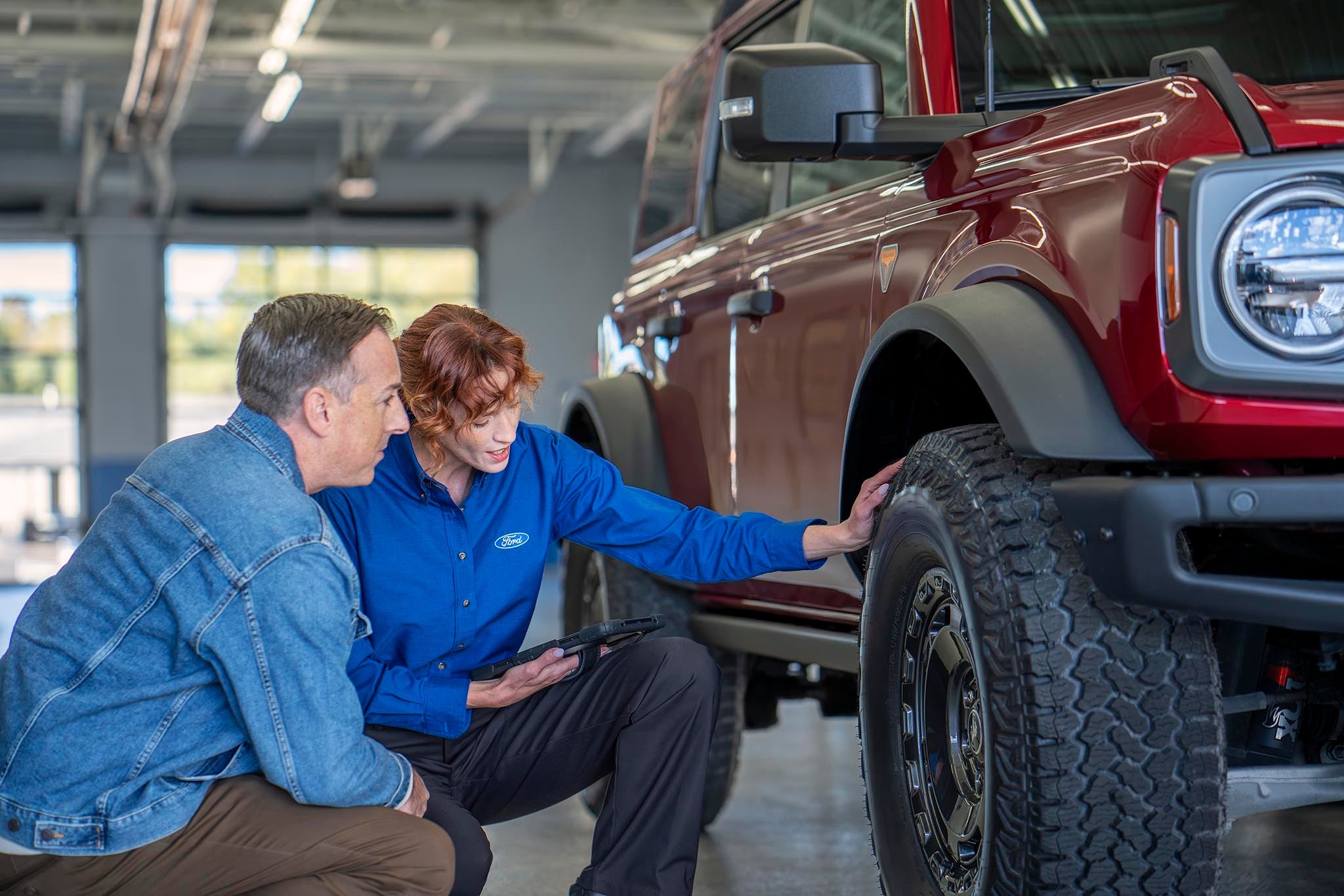 Ford service representative and vehicle owner checking tire wear