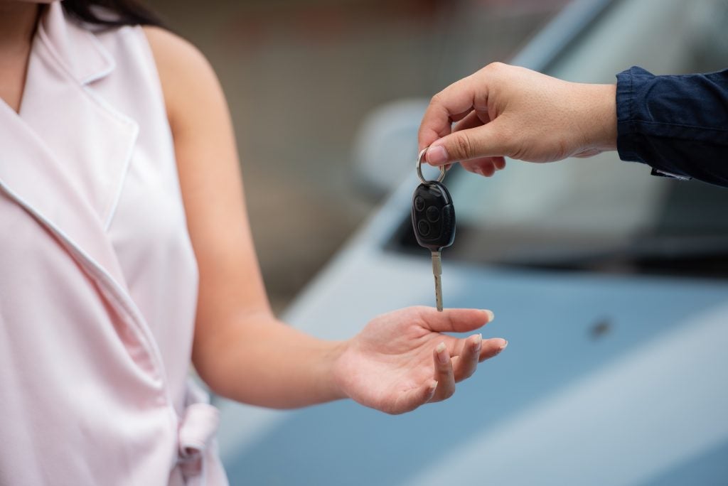 Car salesman handing car keys over to a woman.