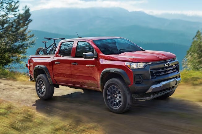 A red 2024 Chevrolet Colorado driving in the mountains.