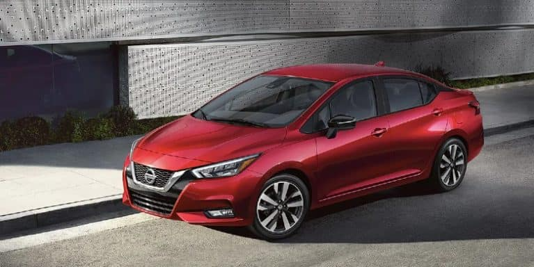 A Red 2021 Nissan Versa is parked on a city street
