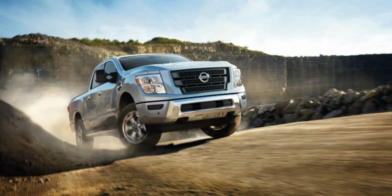 A Nissan Titan XD drives up a dirt hill.