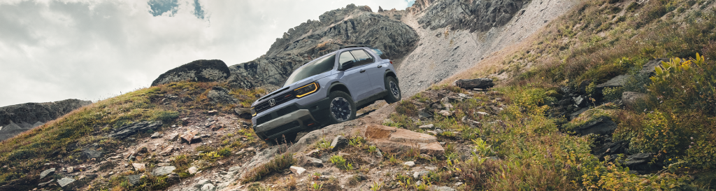 A 2026 Honda Passport driving off-road down a hill on rocky terrain