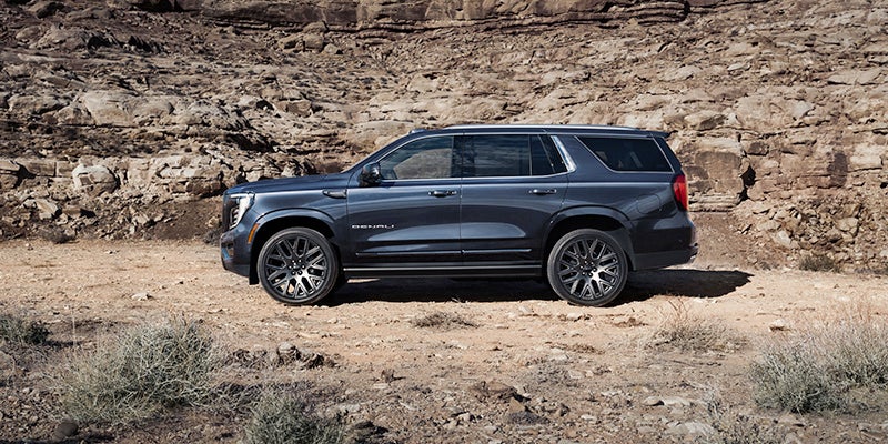 2025 GMC Yukon parked in front of a rocky incline