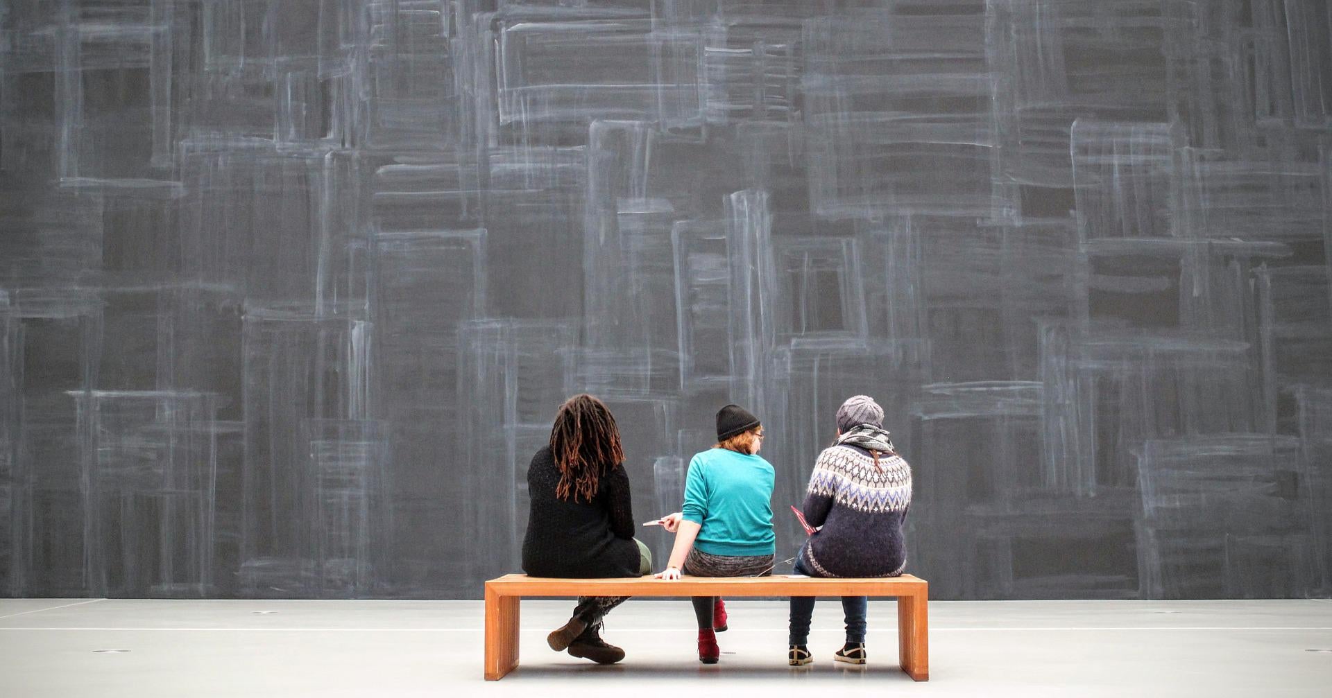 Three people on a bench at a museum