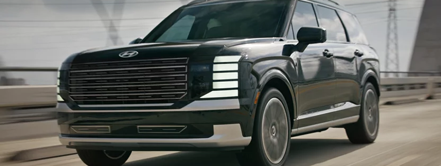 A dark green Hyundai Palisade driving across a city bridge