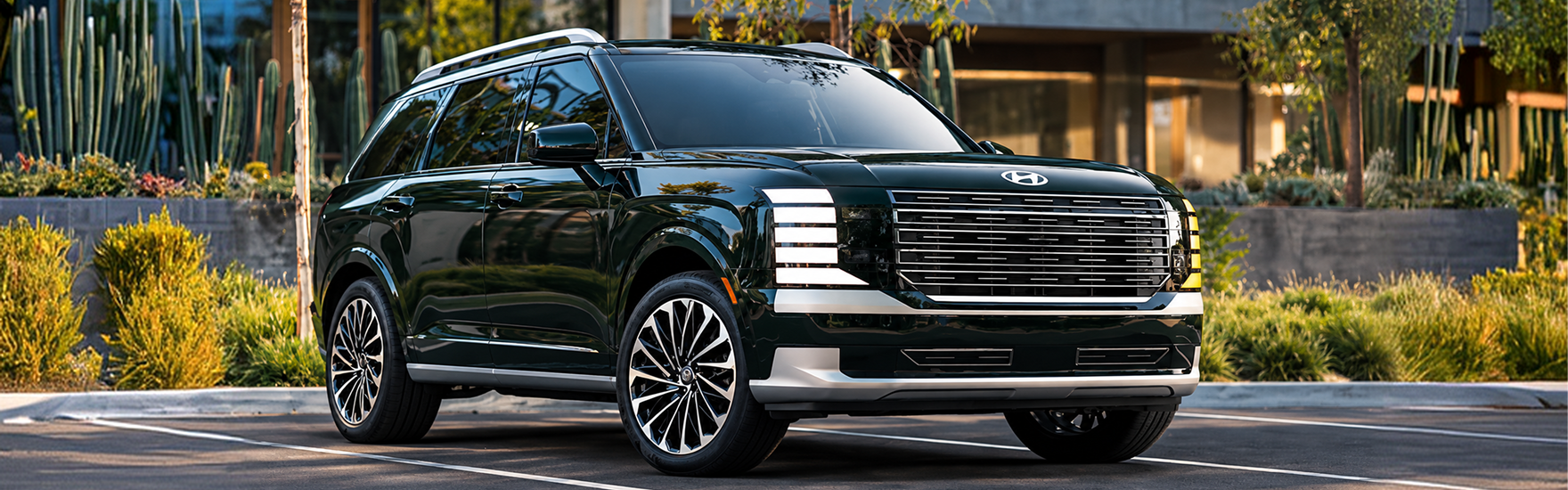 A dark green 2027 Hyundai Palisade parked in front of a desert garden